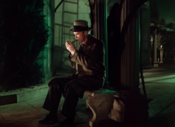 Movie still from “Doctor X” (1932), directed by Michael Curtiz – A man sitting on top of a bench in a dark room; Wide shot, High angle