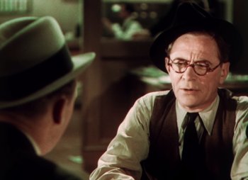Movie still from “Doctor X” (1932), directed by Michael Curtiz – An older man wearing a hat and a tie talking to a younger man; Close Up shot, Over the shoulder angle