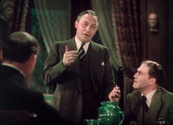 Movie still from “Doctor X” (1932), directed by Michael Curtiz – An older man in a suit and tie talking to a group of people; Medium shot, Over the shoulder angle