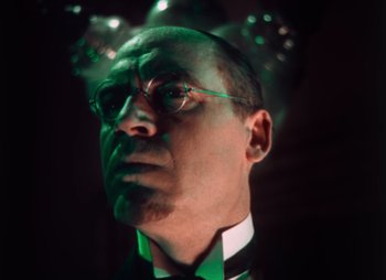 Movie still from “Doctor X” (1932), directed by Michael Curtiz – A person wearing a suit and glasses; Close Up shot, Low angle