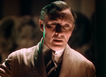 Movie still from “Doctor X” (1932), directed by Michael Curtiz – A man in a suit and tie looking at the camera; Close Up shot, Low angle