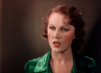 Movie still from “Doctor X” (1932), directed by Michael Curtiz – A woman in a green dress is posing for a picture; Close Up shot, High angle
