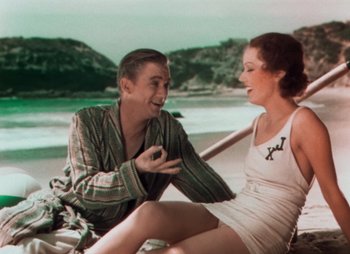 Movie still from “Doctor X” (1932), directed by Michael Curtiz – A man and a woman sitting next to each other on the beach; Medium shot, High angle