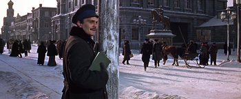 Movie still from “Doctor Zhivago” (1965), directed by David Lean – A man standing next to a pole in the middle of a snowy street; Medium shot, Low angle