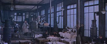 Movie still from “Doctor Zhivago” (1965), directed by David Lean – People are sitting at tables in an industrial setting; Wide shot, High angle