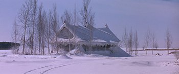 Movie still from “Doctor Zhivago” (1965), directed by David Lean – A house that is covered in snow near a bunch of trees; Extreme Wide shot, High angle