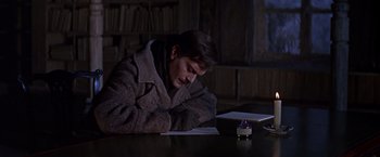 Movie still from “Doctor Zhivago” (1965), directed by David Lean – A man sitting at a table writing on a piece of paper; Medium shot, High angle