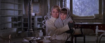 Movie still from “Doctor Zhivago” (1965), directed by David Lean – A woman and a child pose for a picture in front of a table; Medium shot, Low angle
