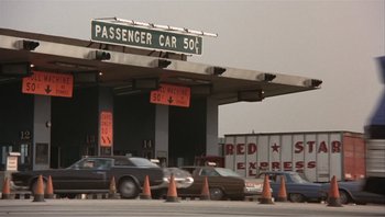 Movie still from “Dog Day Afternoon” (1975), directed by Sidney Lumet – Cars are parked at a toll booth on the side of the road; Extreme Wide shot, High angle