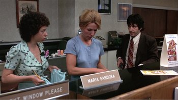 Movie still from “Dog Day Afternoon” (1975), directed by Sidney Lumet – A woman standing in front of two men at a counter; Medium shot, Low angle