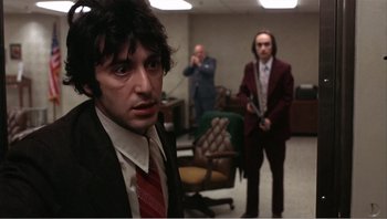 Movie still from “Dog Day Afternoon” (1975), directed by Sidney Lumet – A man in a suit and tie in an office setting; Medium shot, Low angle