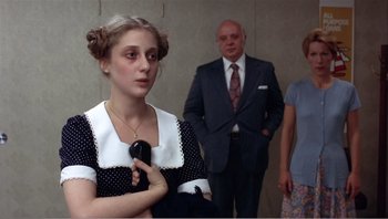 Movie still from “Dog Day Afternoon” (1975), directed by Sidney Lumet – A woman holding a cell phone while standing next to two men; Medium shot, Over the shoulder angle