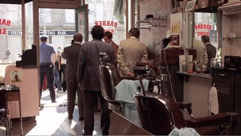 Movie still from “Dog Day Afternoon” (1975), directed by Sidney Lumet – A group of people standing in front of a barber shop; Wide shot, High angle