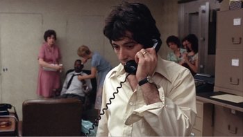 Movie still from “Dog Day Afternoon” (1975), directed by Sidney Lumet – A man talking on a phone while standing in a room; Close Up shot, Over the shoulder angle