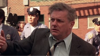 Movie still from “Dog Day Afternoon” (1975), directed by Sidney Lumet – A man in a suit and tie next to another man in a police uniform; Close Up shot, Over the shoulder angle