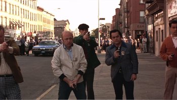 Movie still from “Dog Day Afternoon” (1975), directed by Sidney Lumet – A group of men standing on a sidewalk; Wide shot, Low angle