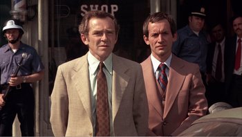 Movie still from “Dog Day Afternoon” (1975), directed by Sidney Lumet – A couple of men standing next to each other in suits; Medium shot, Low angle