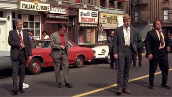 Movie still from “Dog Day Afternoon” (1975), directed by Sidney Lumet – A man in a suit and tie standing on the side of the street; Wide shot, Low angle