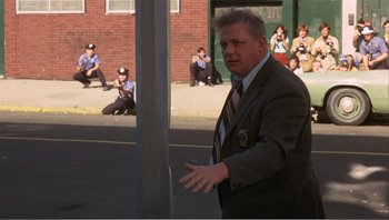 Movie still from “Dog Day Afternoon” (1975), directed by Sidney Lumet – A man wearing a suit and tie standing next to a pole; Wide shot, High angle