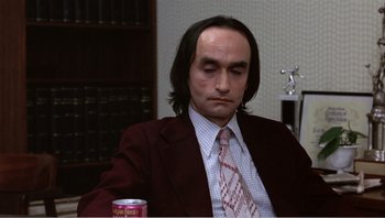 Movie still from “Dog Day Afternoon” (1975), directed by Sidney Lumet – A man in a suit and tie sitting at a table with a drink; Medium shot, High angle