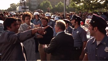 Movie still from “Dog Day Afternoon” (1975), directed by Sidney Lumet – A group of people standing in front of a group of police officers; Medium shot, Over the shoulder angle