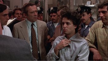 Movie still from “Dog Day Afternoon” (1975), directed by Sidney Lumet – A group of men standing next to each other in a room; Medium shot, Over the shoulder angle