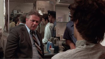 Movie still from “Dog Day Afternoon” (1975), directed by Sidney Lumet – A man in a suit and tie talking to a man in a suit and tie; Medium shot, Over the shoulder angle