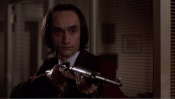 Movie still from “Dog Day Afternoon” (1975), directed by Sidney Lumet – A man in a suit and tie holding a gun; Medium shot, Low angle