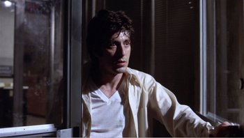 Movie still from “Dog Day Afternoon” (1975), directed by Sidney Lumet – A man in a white shirt leaning against a window sill; Medium shot, Low angle