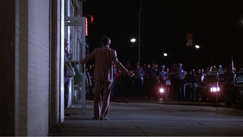 Movie still from “Dog Day Afternoon” (1975), directed by Sidney Lumet – A man standing in front of a crowd at night; Wide shot, Over the shoulder angle