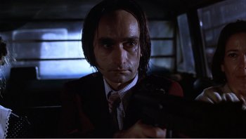 Movie still from “Dog Day Afternoon” (1975), directed by Sidney Lumet – A man in a suit and tie holding a gun; Close Up shot, Low angle