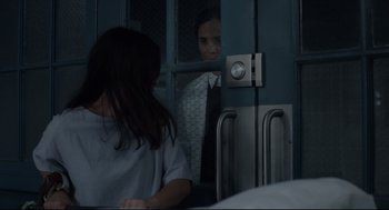 Movie still from “The New Mutants” (2020), directed by Josh Boone – A woman looking through a window at another woman; Medium shot, Over the shoulder angle