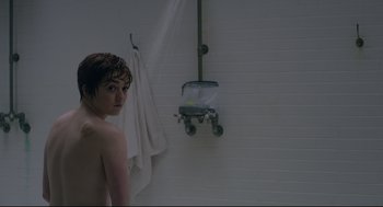 Movie still from “The New Mutants” (2020), directed by Josh Boone – A person standing in a bathroom next to a shower; Medium shot, Over the shoulder angle