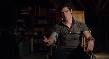 Movie still from “The New Mutants” (2020), directed by Josh Boone – A man sitting in a chair holding a remote control; Medium shot, High angle