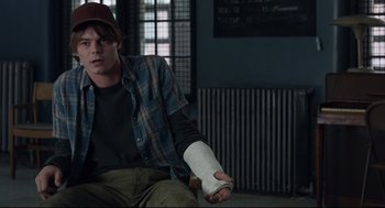 Movie still from “The New Mutants” (2020), directed by Josh Boone – A man with a bandaged arm sitting on the ground; Medium shot, Over the shoulder angle