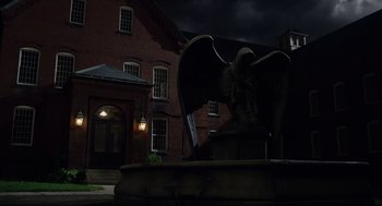 Movie still from “The New Mutants” (2020), directed by Josh Boone – A statue of an angel in front of a brick building at night; Extreme Wide shot, Low angle