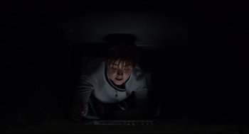 Movie still from “The New Mutants” (2020), directed by Josh Boone – A young boy is laying in the dark looking at a computer screen; Medium shot, Overhead angle