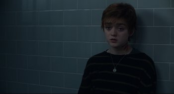 Movie still from “The New Mutants” (2020), directed by Josh Boone – A young man with a necklace is standing in front of a brick wall; Close Up shot, High angle