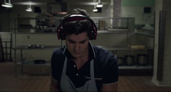 Movie still from “The New Mutants” (2020), directed by Josh Boone – A young man wearing headphones while wearing an apron; Close Up shot, High angle