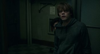 Movie still from “The New Mutants” (2020), directed by Josh Boone – A young man in a gray hoodie standing next to a wall; Medium shot, Over the shoulder angle