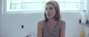 Movie still from “Dogtooth” (2009), directed by Yorgos Lanthimos – A woman sitting in front of a window in a room; Close Up shot, Low angle
