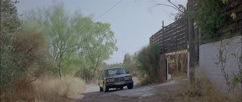 Movie still from “Dogtooth” (2009), directed by Yorgos Lanthimos – A car is driving down a dirt road near trees; Extreme Wide shot, Low angle