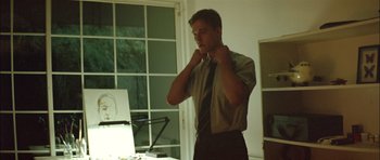 Movie still from “Dogtooth” (2009), directed by Yorgos Lanthimos – A man in a tie is standing in front of a window; Medium shot, Low angle