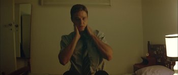 Movie still from “Dogtooth” (2009), directed by Yorgos Lanthimos – A man sitting on the ground with his hands on his face; Medium shot, Low angle