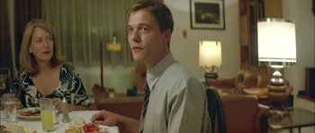 Movie still from “Dogtooth” (2009), directed by Yorgos Lanthimos – A man sitting at a table with food in front of him; Close Up shot, Low angle