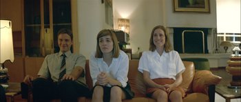 Movie still from “Dogtooth” (2009), directed by Yorgos Lanthimos – A group of people sitting on top of a brown couch; Medium shot, High angle