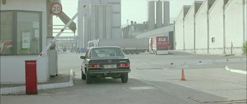 Movie still from “Dogtooth” (2009), directed by Yorgos Lanthimos – A car driving down a street next to a street sign; Wide shot, Low angle