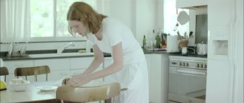Movie still from “Dogtooth” (2009), directed by Yorgos Lanthimos – A woman in a white apron standing in a kitchen; Medium shot, Low angle