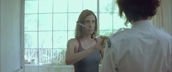 Movie still from “Dogtooth” (2009), directed by Yorgos Lanthimos – A woman holding a knife in front of her face; Medium shot, Over the shoulder angle