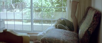 Movie still from “Dogtooth” (2009), directed by Yorgos Lanthimos – A woman laying on a bed in front of a window; Medium shot, High angle